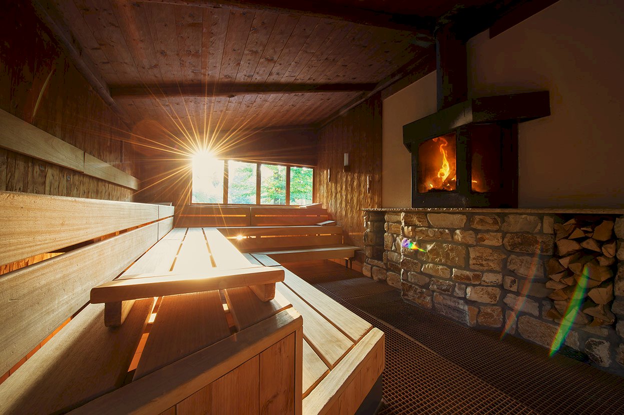 Holzsauna mit Ofen und warmem Sonnenlicht